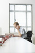Photo: Office worker sitting using mobile phone at desk with document trays, side view Office worker sitting using mobile phone at desk with document trays, side view