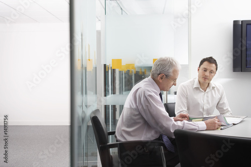 Photo: Mature businessman and office worker sitting at conference table Mature businessman and office worker sitting at conference table