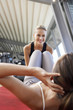 Woman holding legs of woman doing sit ups in health club