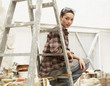 Female interior decorator sitting on ladder in work site, portrait