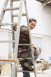Female interior decorator sitting on ladder in work site, portrait