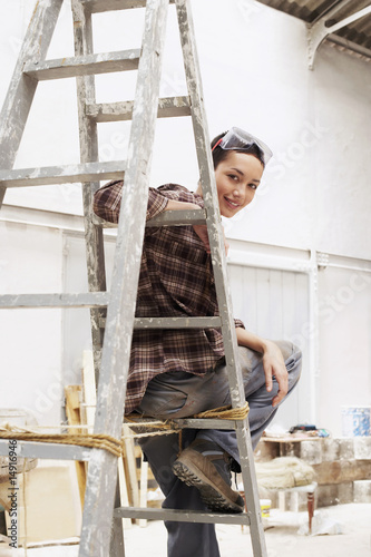 Photo: Female interior decorator sitting on ladder in work site, portrait Female interior decorator sitting on ladder in work site, portrait