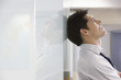 Photo: Unhappy Businessman leaning back against office wall and looking at ceiling, side view Unhappy Businessman leaning back against office wall and looking at ceiling, side view
