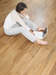 Woman sat on wood panel floor using laptop