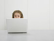 Small girl by desk using laptop