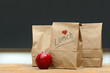 Lunch bags with apple on school desk Lunch bags with apple on school desk
