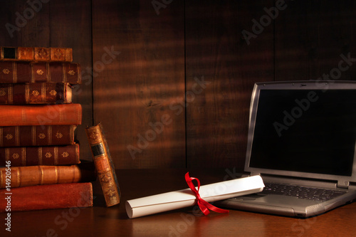 Photo: Antique books, diploma with laptop on desk Antique books, diploma with laptop on desk