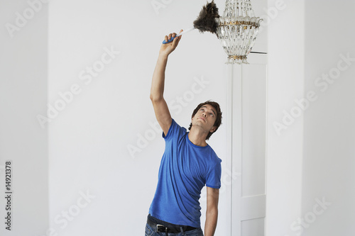 Photo: Man dusting crystal chandelier in home Man dusting crystal chandelier in home