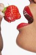 Close up of woman with shiny red lips about to bite into a juicy strawberry