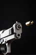 Gun shooting bullet on black background, close up