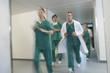 Motion blur image of small group of doctors and nurses in scrubs running through hospital corridor