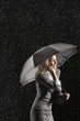 Businesswoman standing under umbrella, talking on mobile