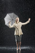 Woman standing in overcoat, holding umbrella, singing in the rain