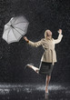 Woman standing on one leg, holding umbrella, leaning into falling rain