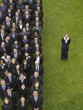 Photo: Business woman standing next to large group of business people in formation, elevated view, portrait Business woman standing next to large group of business people in formation, elevated view, portrait