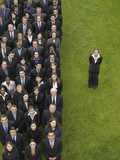 Photo: Business woman standing next to large group of business people in formation, elevated view, portrait Business woman standing next to large group of business people in formation, elevated view, portrait