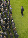 Photo: Business man facing large group of business people in formation, elevated view Business man facing large group of business people in formation, elevated view