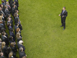 Photo: Business man facing large group of business people in formation, elevated view Business man facing large group of business people in formation, elevated view