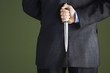 Photo: Mid-adult businessman standing, holding knife behind back, mid section, back view Mid-adult businessman standing, holding knife behind back, mid section, back view