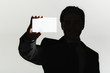 Silhouetted man standing, holding large blank card