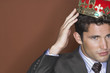 Man putting on crown against brown background, close-up