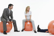 Two people sitting on space hoppers looking at fallen man, against white background