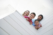 Family peering over white wall, view from below
