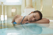 Young woman with eyes closed leaning on edge of swimming pool, portrait