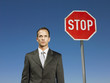 Businessman standing next to stop sign, half length