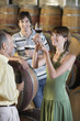 Three people wine-tasting beside wine casks