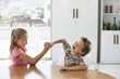 Young girl and boy fighting at table at home