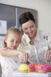 Mother and Daughter Decorating Cupcakes in kitchen