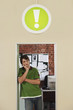 Foto: Young man standing in doorway of office, with sign of exclamation mark above. Young man standing in doorway of office, with sign of exclamation mark above.