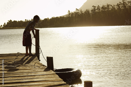 Photo: Boy 7-9 standing on dock, pulling in float tube. Boy 7-9 standing on dock, pulling in float tube.