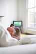 Mother and daughter 5-6 watching cartoons in television, back view
