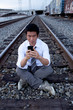 Asian man making call on train tracks Asian man making call on train tracks