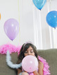 Foto: Young girl 7-9 sitting on sofa, blowing up balloon Young girl 7-9 sitting on sofa, blowing up balloon