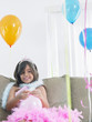 Foto: Young girl 7-9 on sofa preparing birthday balloons Young girl 7-9 on sofa preparing birthday balloons