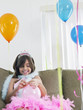 Foto: Young girl 7-9 on sofa preparing birthday balloons Young girl 7-9 on sofa preparing birthday balloons