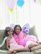 Foto: Portrait of two girls 7-9, 10-12 sitting on sofa in party costumes Portrait of two girls 7-9, 10-12 sitting on sofa in party costumes