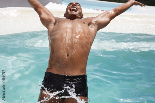 Photo: Man in diving backwards into swimming pool, smiling, half length Man in diving backwards into swimming pool, smiling, half length