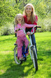 laughing girl on bicycle with mother in spring garden laughing girl on bicycle with mother in spring garden