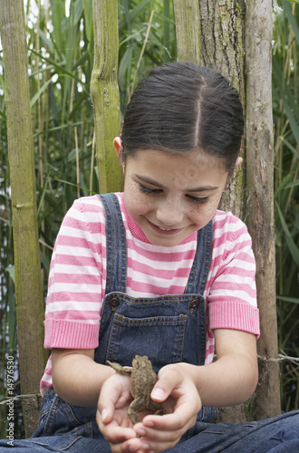 Foto: Girl 5-6 holding toad by fence Girl 5-6 holding toad by fence
