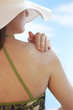 Woman applying sunscreen to shoulder, back view