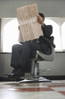 Business man reading newspaper, waiting in barber shop