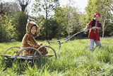 Photo: Young boy 7-9 in pirate costume pulling boy 5-6 in jaguar costume sitting on cart, smiling Young boy 7-9 in pirate costume pulling boy 5-6 in jaguar costume sitting on cart, smiling