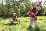Photo: Young boy 7-9 in pirate costume pulling boy 5-6 in jaguar costume sitting on cart, smiling Young boy 7-9 in pirate costume pulling boy 5-6 in jaguar costume sitting on cart, smiling