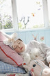 Young girl 5-6 in unicorn costume sleeping on bed with toy horse