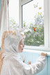 Profile of young girl 5-6 in unicorn costume opening door, smiling