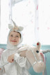 Photo: Portrait of young girl 5-6 in unicorn costume holding toy horse, smiling, indoors Portrait of young girl 5-6 in unicorn costume holding toy horse, smiling, indoors